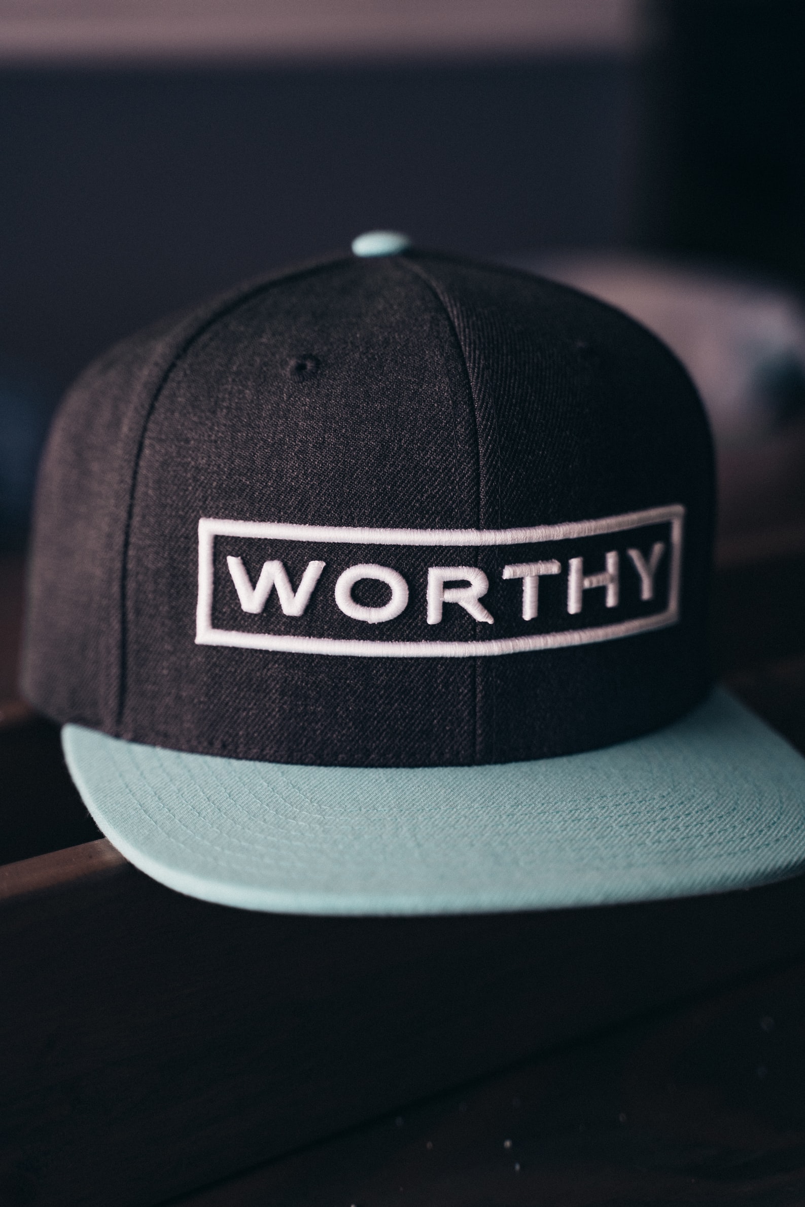 black and teal cap with the words worthy